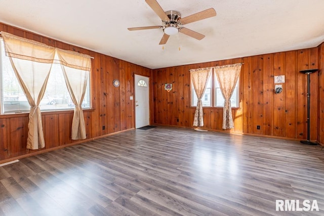 interior space with wooden walls, dark hardwood / wood-style floors, and a wealth of natural light