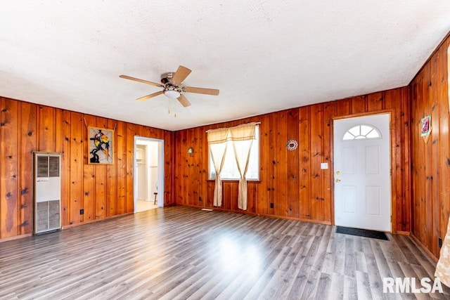 foyer entrance featuring ceiling fan, wood walls, light wood-type flooring, and a textured ceiling