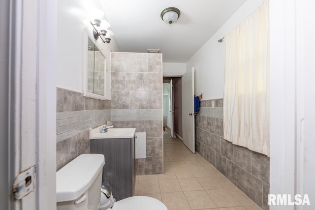 bathroom featuring tile patterned floors, vanity, toilet, and tile walls