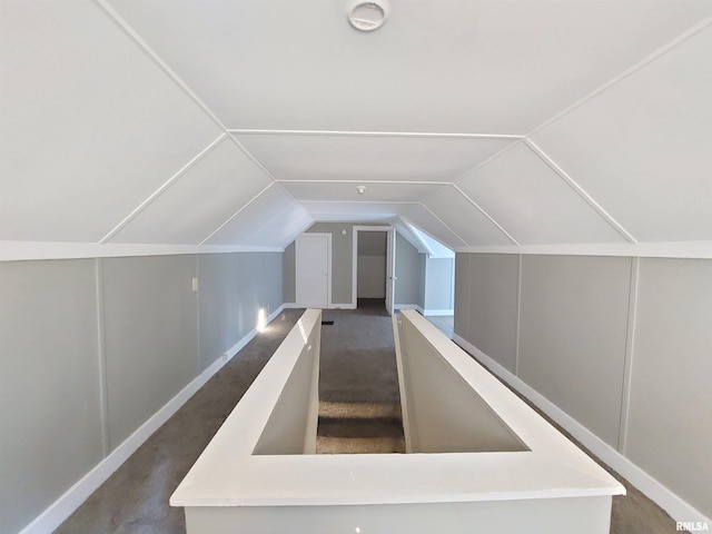 additional living space featuring lofted ceiling and dark colored carpet