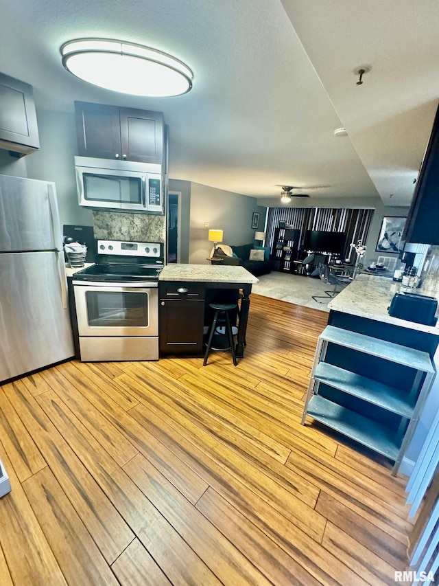 kitchen with ceiling fan, backsplash, stainless steel appliances, and light wood-type flooring