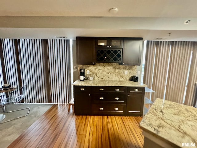 kitchen featuring light hardwood / wood-style flooring, decorative backsplash, light stone counters, and dark brown cabinetry