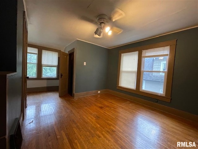 unfurnished room featuring wooden walls, ceiling fan, and hardwood / wood-style flooring