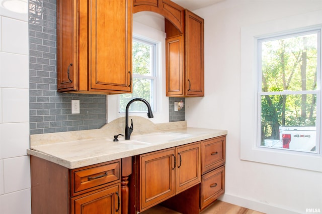 kitchen featuring backsplash, light stone counters, plenty of natural light, and sink