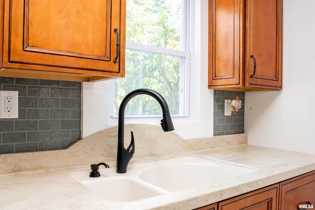 interior details with light stone countertops, tasteful backsplash, and sink