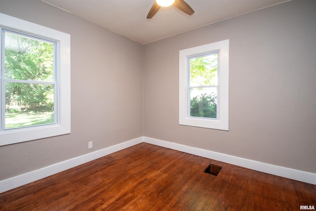 empty room with a healthy amount of sunlight, ceiling fan, and hardwood / wood-style floors