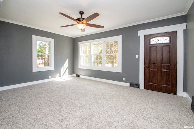 carpeted foyer featuring crown molding and ceiling fan