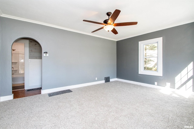 empty room with ornamental molding, ceiling fan, and carpet floors