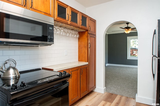 kitchen with ceiling fan, appliances with stainless steel finishes, light hardwood / wood-style floors, and decorative backsplash