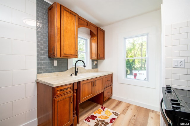 kitchen featuring light stone countertops, light wood-type flooring, sink, and decorative backsplash