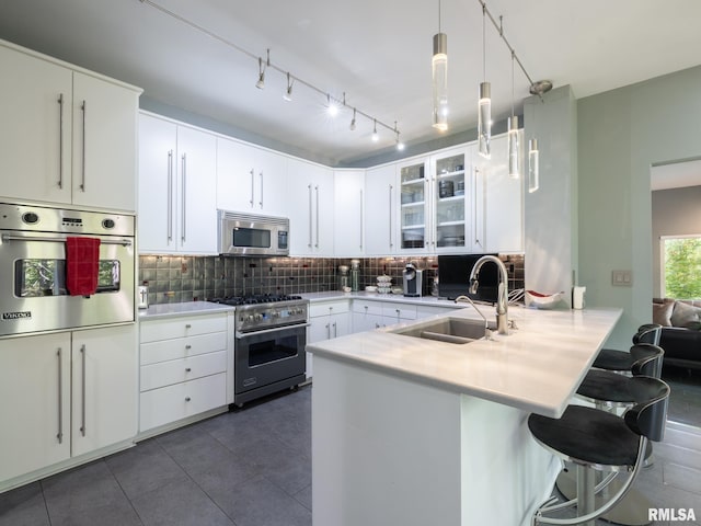 kitchen featuring decorative light fixtures, white cabinetry, a kitchen breakfast bar, decorative backsplash, and appliances with stainless steel finishes