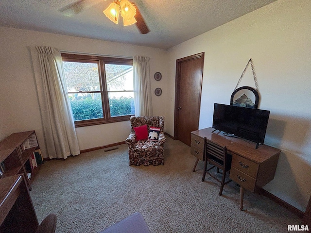 carpeted office with a textured ceiling and ceiling fan