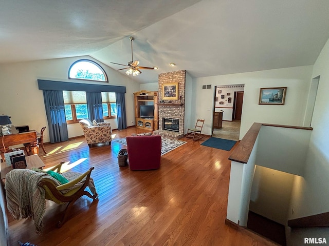 living room featuring ceiling fan, a fireplace, vaulted ceiling, and wood-type flooring