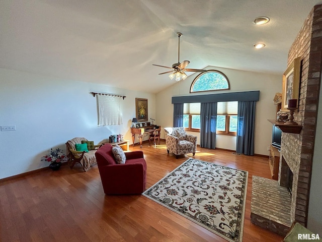 living room featuring wood-type flooring, lofted ceiling, ceiling fan, and a fireplace