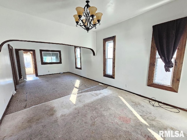 unfurnished room with carpet flooring and a chandelier