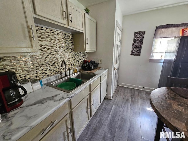 kitchen with backsplash, light stone counters, dark wood-type flooring, and sink