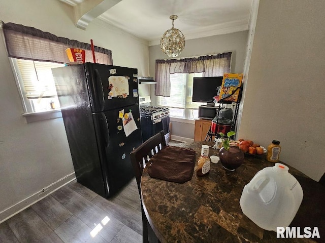 kitchen with black refrigerator, white range with gas cooktop, hardwood / wood-style flooring, ornamental molding, and a chandelier