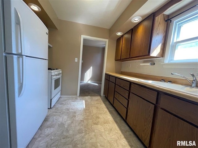 kitchen featuring backsplash, white appliances, and sink