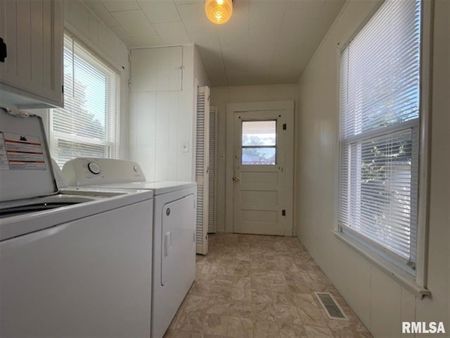 laundry area with separate washer and dryer and cabinets