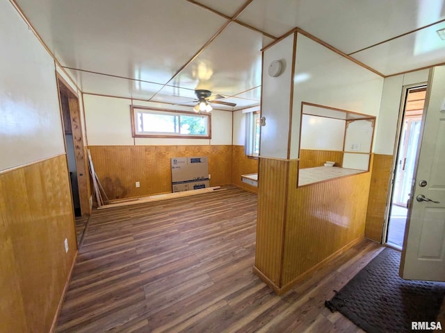 interior space with wooden walls, ceiling fan, dark hardwood / wood-style floors, and heating unit