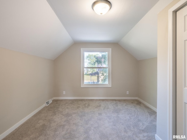 additional living space featuring lofted ceiling and light carpet