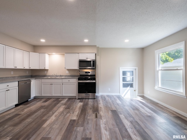 kitchen with white cabinets, sink, appliances with stainless steel finishes, and dark hardwood / wood-style flooring