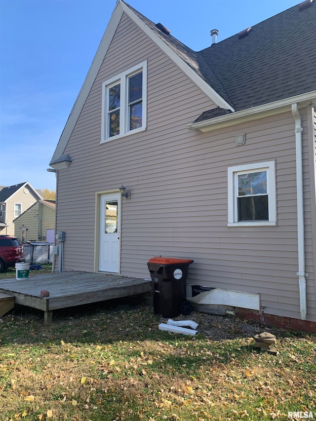 back of house with a deck and a lawn