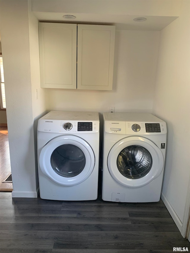 laundry area featuring cabinets, dark hardwood / wood-style flooring, and washer and clothes dryer