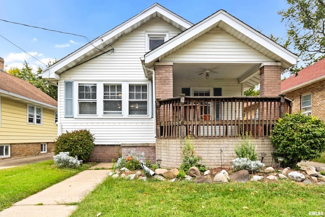 bungalow featuring ceiling fan, a deck, and a front lawn