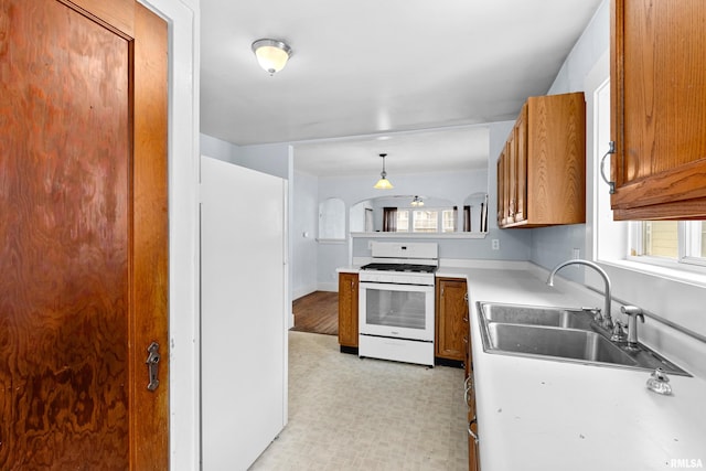 kitchen with hanging light fixtures, sink, white appliances, and a healthy amount of sunlight