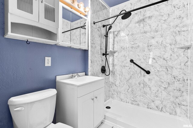 bathroom with toilet, vanity, and tiled shower