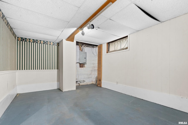 basement with electric panel and a drop ceiling