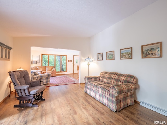 living room with a baseboard heating unit, lofted ceiling, and light wood-type flooring