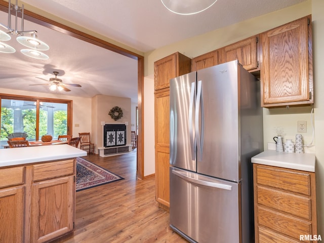 kitchen with stainless steel refrigerator, ceiling fan with notable chandelier, and light wood-type flooring