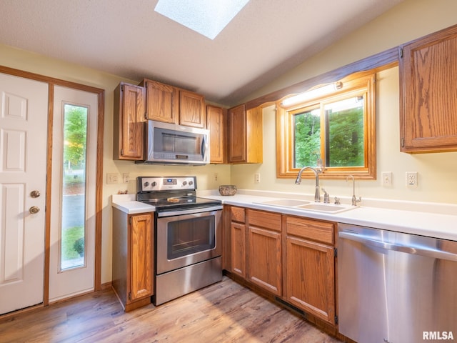 kitchen with lofted ceiling with skylight, sink, stainless steel appliances, and a wealth of natural light