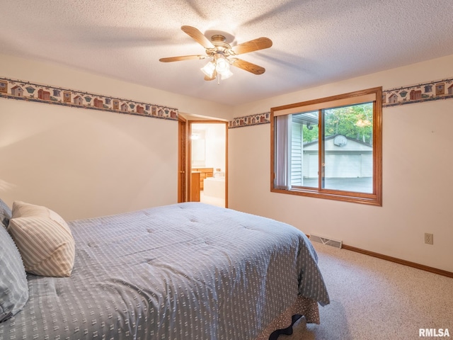 bedroom featuring ceiling fan, a textured ceiling, ensuite bath, and carpet