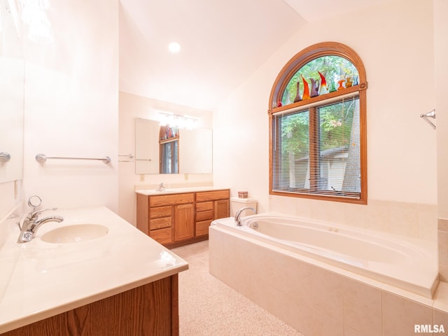 bathroom featuring lofted ceiling, tiled tub, and vanity