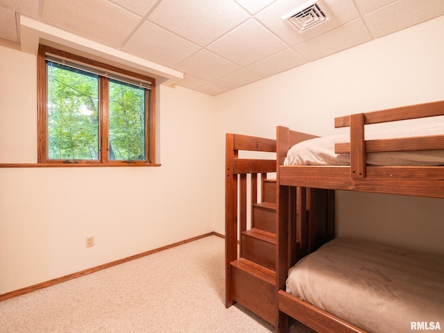 unfurnished bedroom featuring light colored carpet and a drop ceiling