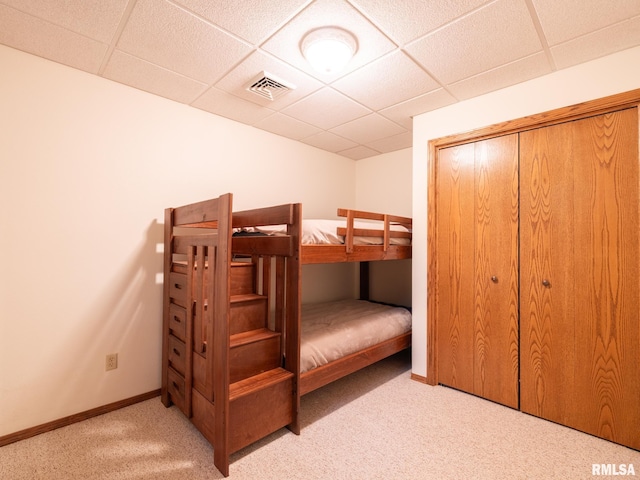 bedroom featuring light carpet, a closet, and a paneled ceiling