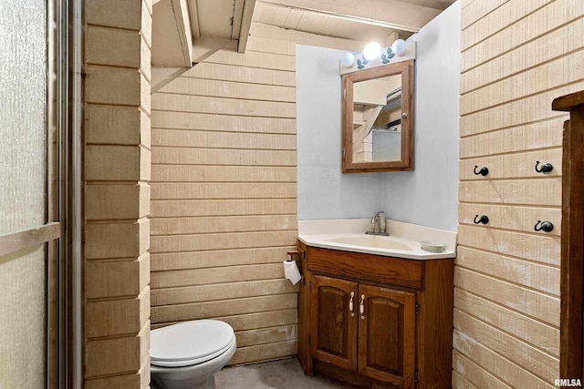 bathroom with wood walls, vanity, and toilet