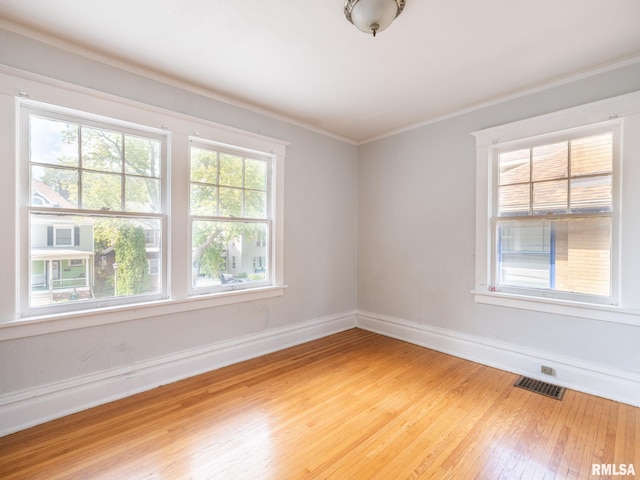 spare room featuring wood-type flooring and crown molding