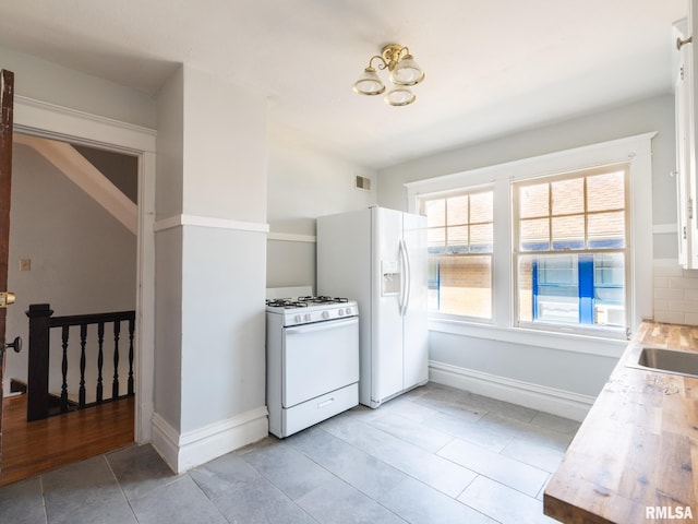 kitchen with white appliances, light tile patterned floors, and backsplash