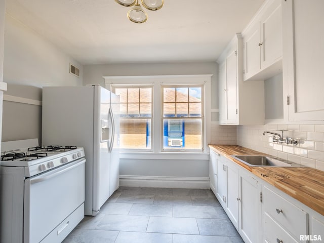 kitchen with white gas range oven, sink, white cabinetry, decorative backsplash, and butcher block countertops