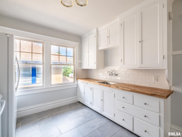 kitchen with white cabinetry, tasteful backsplash, white fridge, wood counters, and sink