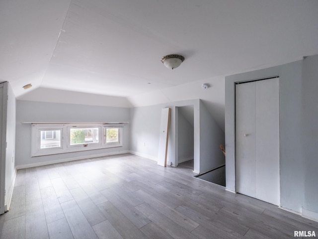 additional living space featuring light wood-type flooring and vaulted ceiling