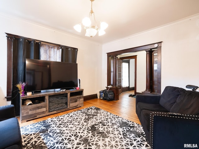 living room featuring light wood-type flooring, crown molding, a chandelier, and ornate columns