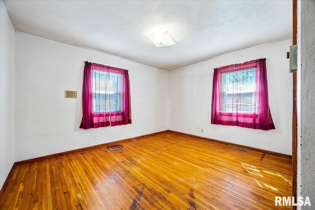 unfurnished room featuring a wealth of natural light and hardwood / wood-style floors