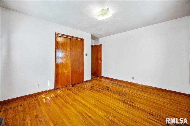 unfurnished bedroom with light hardwood / wood-style flooring and a closet