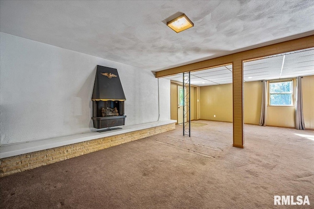 basement with carpet floors, a textured ceiling, and a wood stove