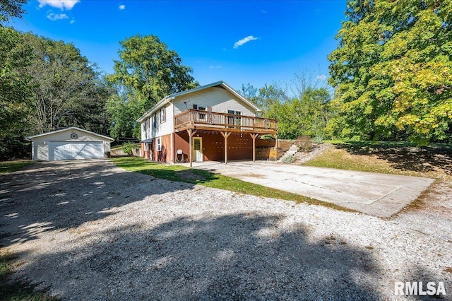 view of property featuring a garage, a wooden deck, and an outbuilding